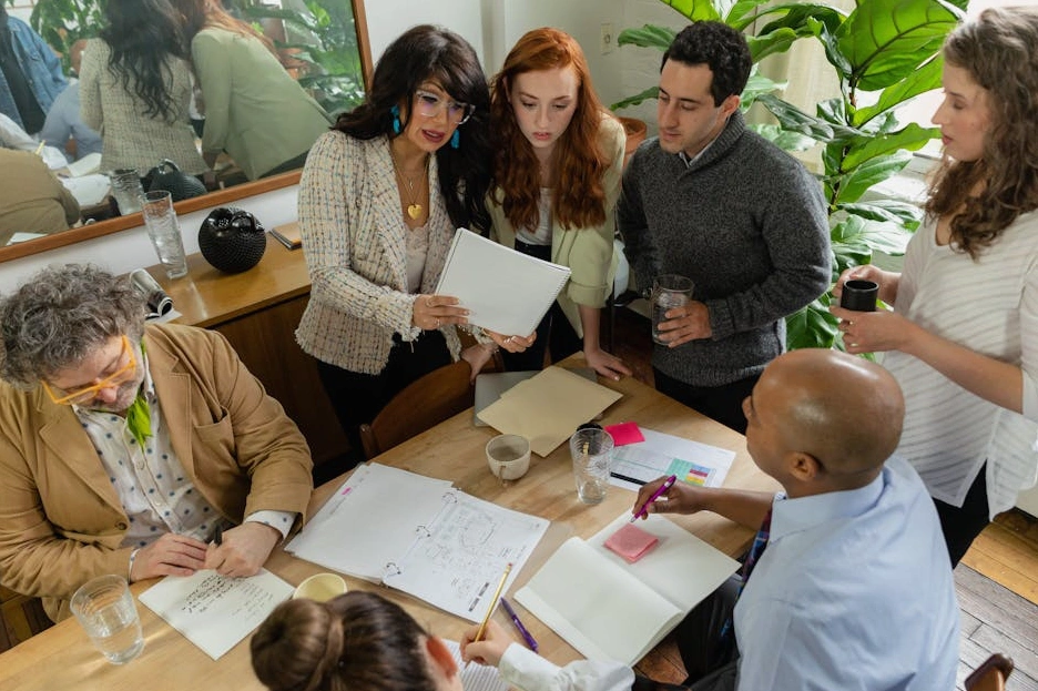 A diverse team of professionals collaborating around a large table with architectural models and city maps
